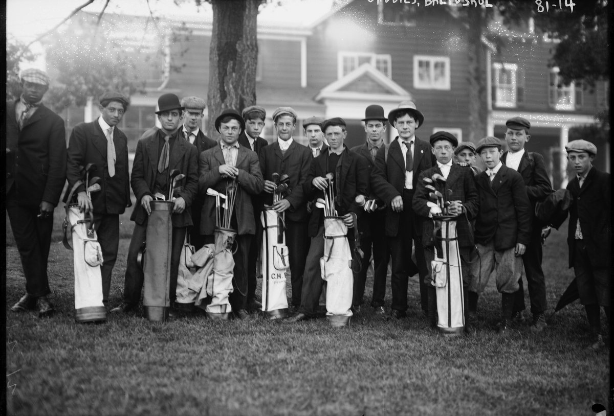 Photographie ancienne d'un groupe de jeunes caddies posant avec des sacs de golf