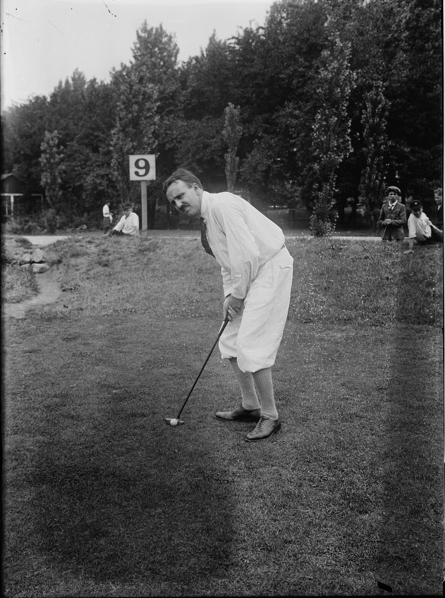 Photographie ancienne d'un golfeur qui putte devant une pancarte numéro 9