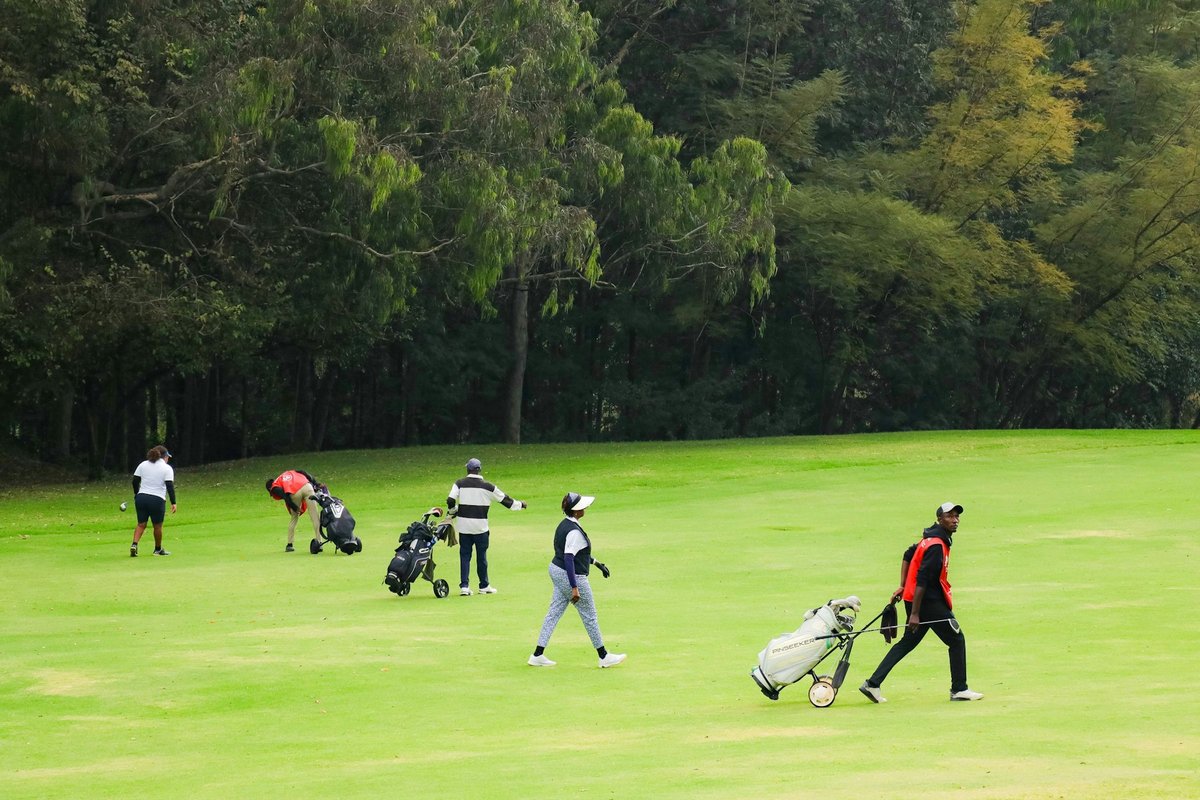 Groupe de joueurs de tous âges traversant un fairway avec leurs sacs