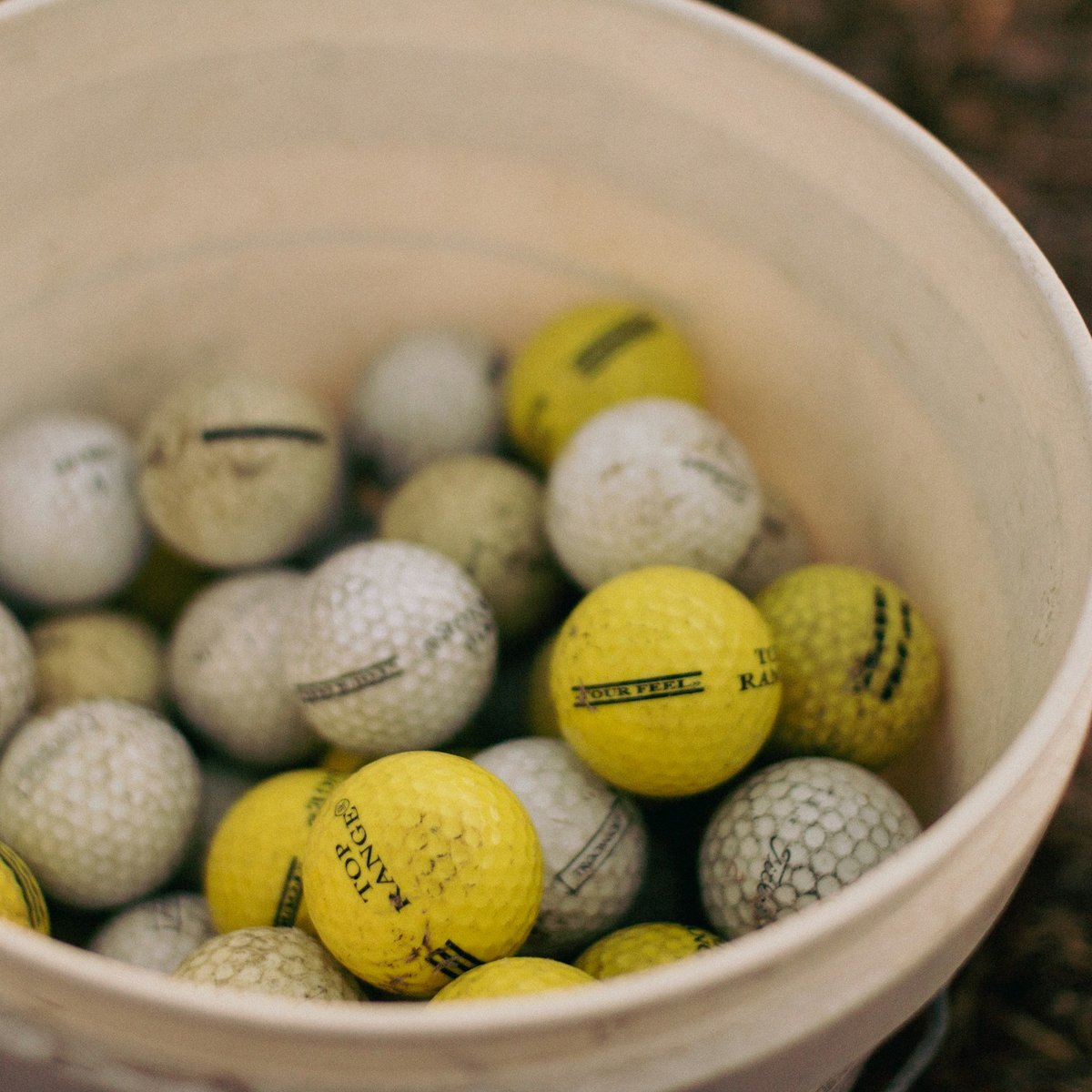 Seau rempli de vieilles balles de golf blanches et jaunes