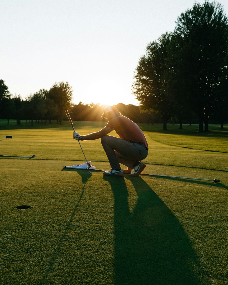 Joueur accroupi sur un green en contre-jour, en fin de journée